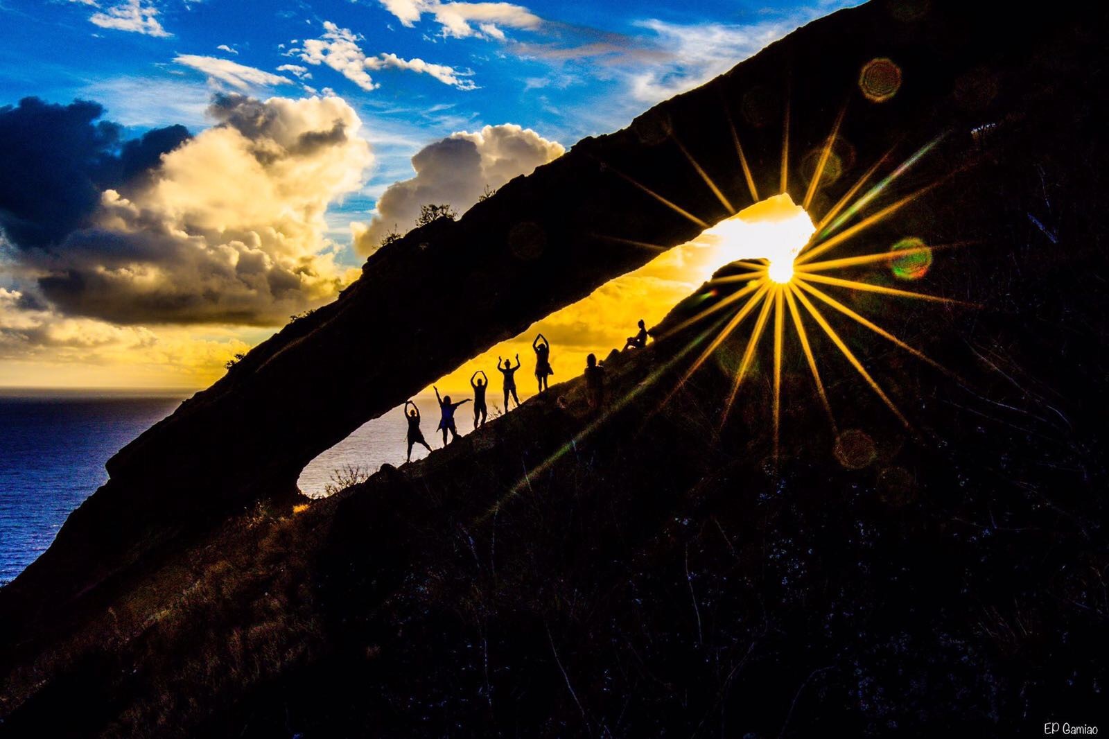 Image of people standing on rock in front of sunset